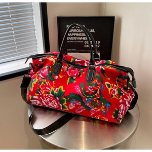 Macro detail of high-capacity travel bag with traditional red floral pattern and leather handles