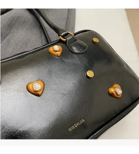 Detail of black leather handbag with gold heart-shaped crystals and metallic studs