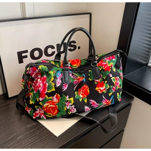 Detail of floral print travel bag with leather handles and colorful phoenix patterns