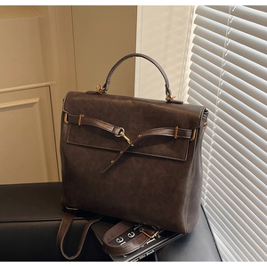 Detail of dark brown vintage leather backpack with metal hook clasp on black bench