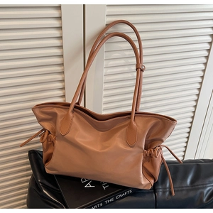 Vue détaillée d'un grand sac fourre-tout en cuir caramel avec cordons sur un livre