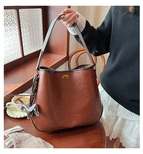 Detail der rotbraunen Leder-Shopper mit goldenem Drehverschluss und Dackel-Anhänger