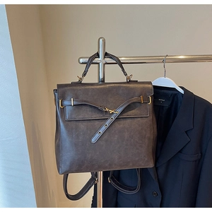 Detail of vintage dark brown leather backpack with gold metal buckles and top handle