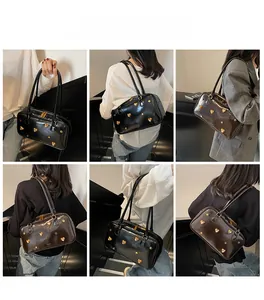 Close-up detail of glossy leather shoulder bag with golden heart-shaped metal studs