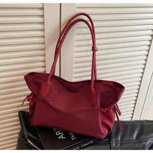 Détail du sac de voyage bordeaux en nylon avec coutures en cuir et cordons latéraux