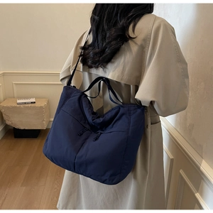 Detail of navy blue nylon tote bag showing its large capacity and soft texture on model
