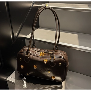 Detailed macro view of dark brown pillow bag with gold heart-shaped rhinestone rivets