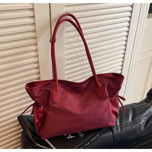 Détail du sac de voyage bordeaux en nylon avec poignées en cuir et cordons latéraux