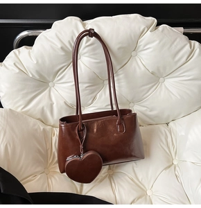 Gros plan d'un sac à bandoulière en cuir marron avec un joli pendentif en forme de cœur