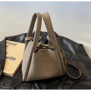 Detail of taupe lychee grain leather bucket bag featuring dual handles and brand logo