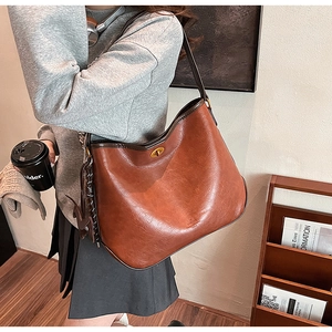 Detail der braunen Leder-Hobo-Tasche mit goldenem Drehverschluss und strukturierter Optik