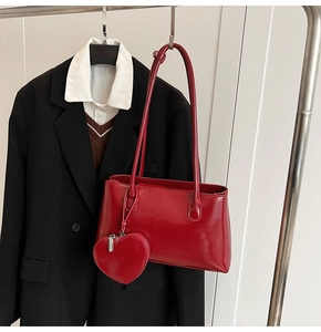 Détail du sac à bandoulière rouge brillant avec une pochette cœur zippée assortie