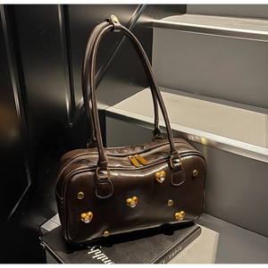 Macro detail of dark brown oil leather bag with golden heart hardware and rivets