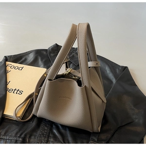 Detail of taupe pebbled leather bucket bag with HAMIROO logo and gold hardware