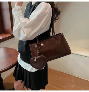 Détail du sac bandoulière en cuir brillant marron foncé avec un porte-monnaie en forme de cœur