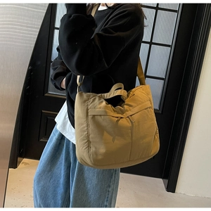 Detail of khaki nylon tote bag showing front zipper pocket and durable canvas texture