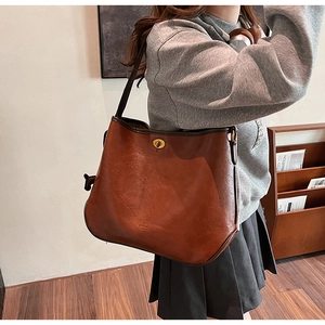 Detailaufnahme einer braunen Vintage-Einkaufstasche mit goldenem Drehverschluss aus Leder