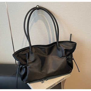 Détail du sac cabas en nylon noir avec côtés à cordon de serrage et finitions en cuir