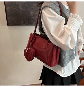 Détail du sac à épaule en cuir verni rouge avec breloque cœur et finition brillante