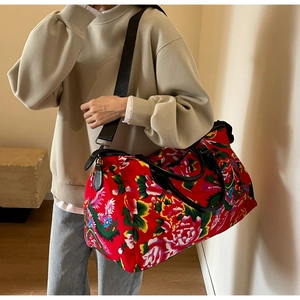Detailed close-up of large travel bag with traditional red floral phoenix patterns