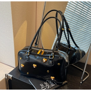 Detail of black glossy leather bag with gold heart studs and sparkling rhinestones
