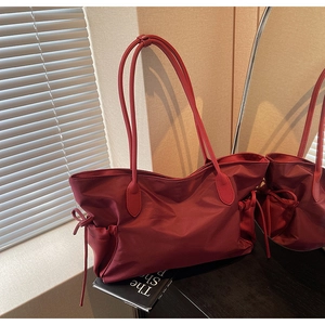 Détail du cabas en nylon bordeaux avec cordons de serrage et anses en cuir