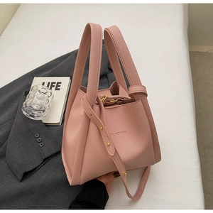 Pink bucket bag with lychee texture featuring double handles and adjustable strap