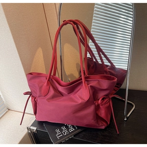 Détail du sac fourre-tout en nylon bordeaux avec poignées en cuir et nœud latéral à cordon