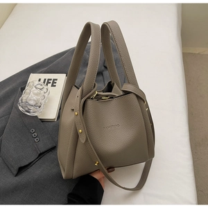 Close-up of elephant grey pebbled leather bucket bag with metallic rivet handles