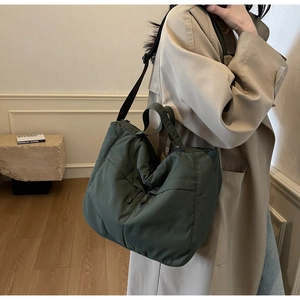 Side view of olive green nylon tote bag on shoulder showing large capacity and strap