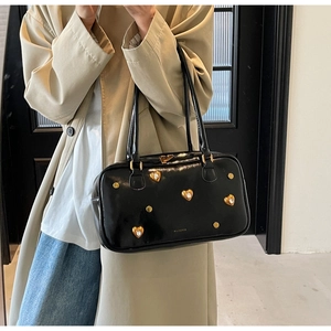Close-up of black retro shoulder bag with gold heart studs and sparkling diamond accents