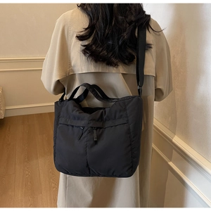 Detail of a large black nylon tote bag showing the dual zipper pockets and shoulder strap