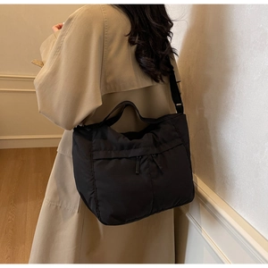 Detailed view of black nylon tote bag with dual front zippers worn by a model