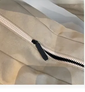 Detail of smooth khaki canvas bag zipper with a black non-slip matte puller close-up