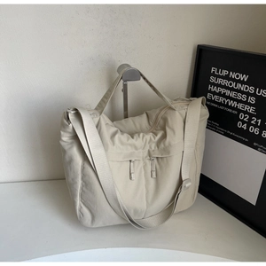 Detail of beige nylon tote bag with two vertical zippers and adjustable shoulder strap