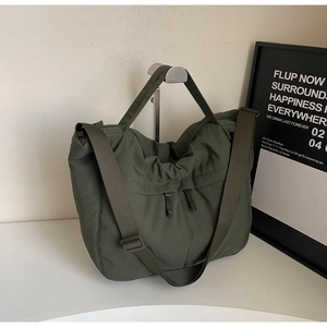 Detail of army green nylon tote bag showing adjustable strap and durable pleated texture