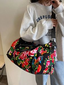 Large travel duffel bag with bold red floral pattern and adjustable crossbody strap