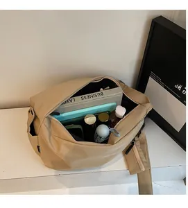 Detail view of beige canvas crossbody bag showing spacious interior with books and tablets