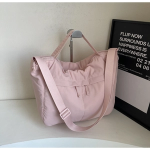 Close-up of soft pink nylon tote bag showing dual vertical zippers and wide strap