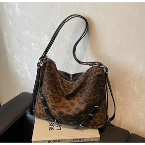 Close-up of leopard print canvas crossbody bag with black leather strap and logo detail