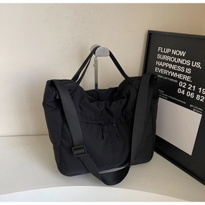 Close-up of waterproof black nylon tote with adjustable strap and dual front zipper pockets