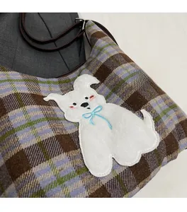 Close-up of retro plaid tote bag with cute cartoon dog patch and brown leather strap