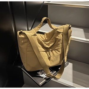Macro shot of khaki nylon tote bag with wide adjustable strap on a book props