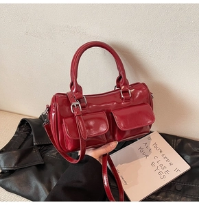 Detail of burgundy glossy leather bowling bag with front pockets and silver hardware