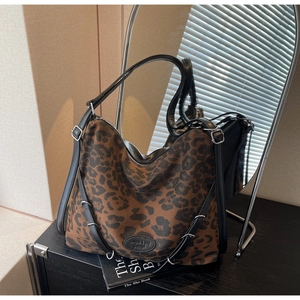 Close-up of leopard print canvas tote with black leather trim and silver metal hardware details
