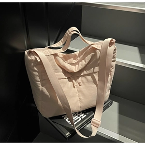 Close-up of pink nylon tote bag with dual front zipper pockets and durable shoulder strap