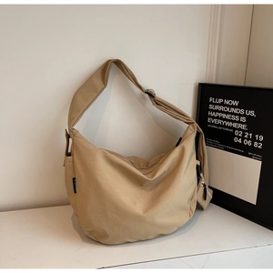 Detail view of khaki canvas hobo bag with adjustable strap and small charm pouch