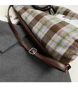 Detail of adjustable leather strap and plaid tweed texture on large tote bag