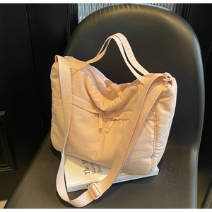 Detail of quilted puffer nylon tote bag showing peach pink texture and adjustable strap