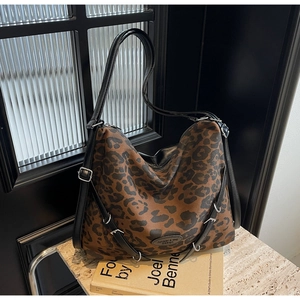Close-up of leopard print tote bag with black leather straps and silver metal buckle
